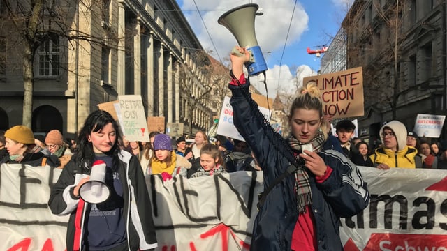 Eine Gruppe Schülerinnen läuft durch Zürich, vorneweg zwei junge Frauen mit einem Megafon in der Hand.