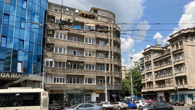 Das einsturzgefährdete Haus: graue Betonfassade verdreckt. Die Fensterrahmen scheinen groteskerweise frisch gestrichen.