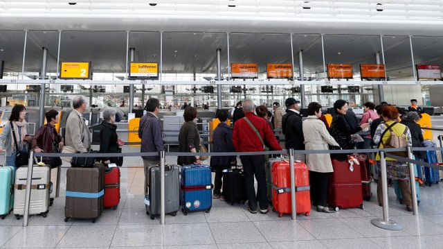 Menschen stehen in einer Schlange vor Lufthansa-Schaltern im Flughafen München