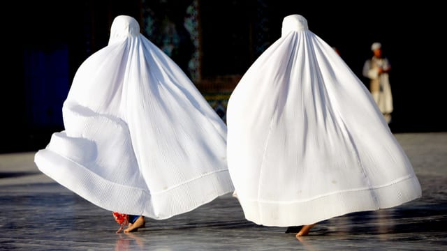 Zwei Frauen von hinten in einer weissen Burka. 