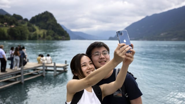 Ein Pärchen nimmt gemeinsam ein Selfie Foto in Iseltwald auf. Im Hintergrund ist ein See zu sehen.