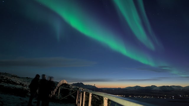 Grünes Polarlichtband über einer Landschaft