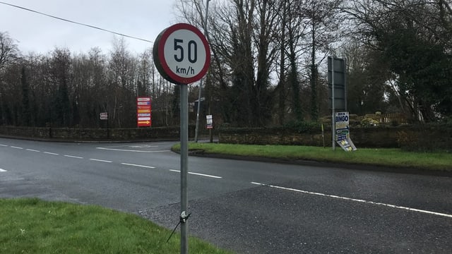 Eine Kreuzung und eine 50-km/h-Tafel. Die Strassen sind nass. Wetter gar nicht schön, ich glaube, es regnet. 