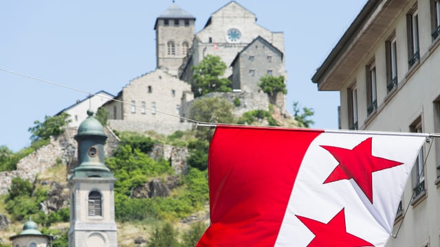 Schloss Valere in Sitten thtront auf dem Hügel, im Vordergrund die Fahne der Stadt