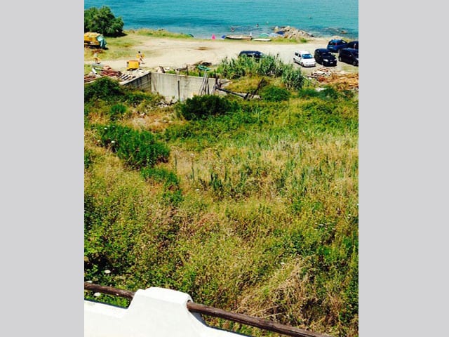 Aussicht aufs Meer, im Vordergrund eine vertrocknete Wiese und eine Baustelle.