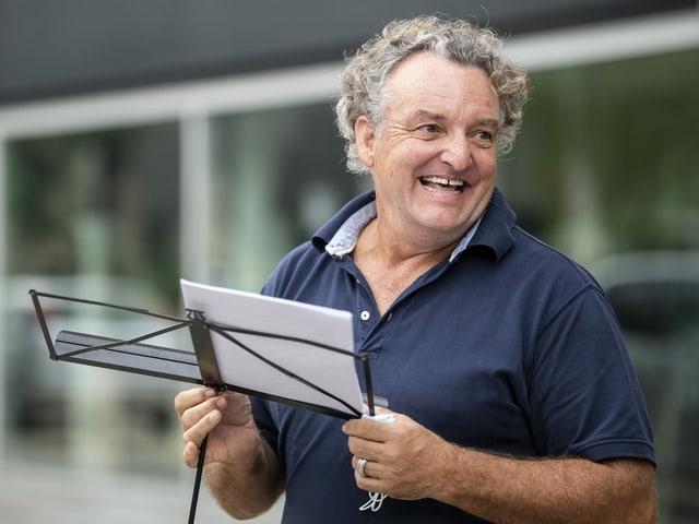 Comedian Marco Rima hält einen Notenständer in der Hand.