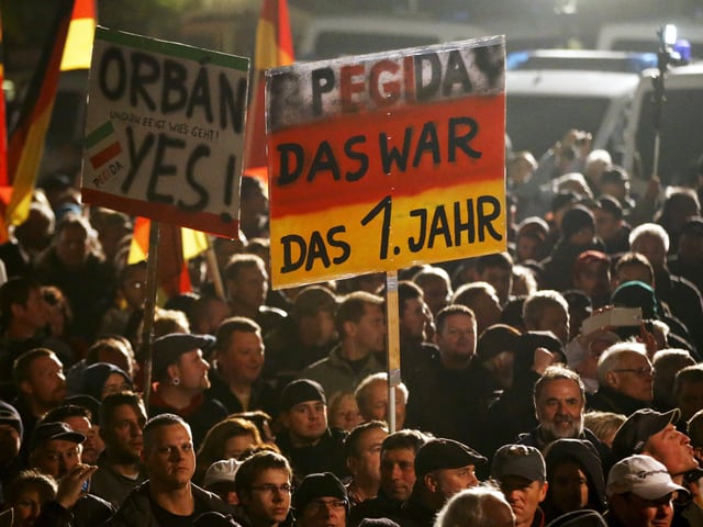 Pegida-Demonstranten am ersten Jahrestag der Kundgebungen. Teilnehmer tragen ein Plakat mit der Aufschrift «Pegida, das war das 1. Jahr» und «Orban, yes».