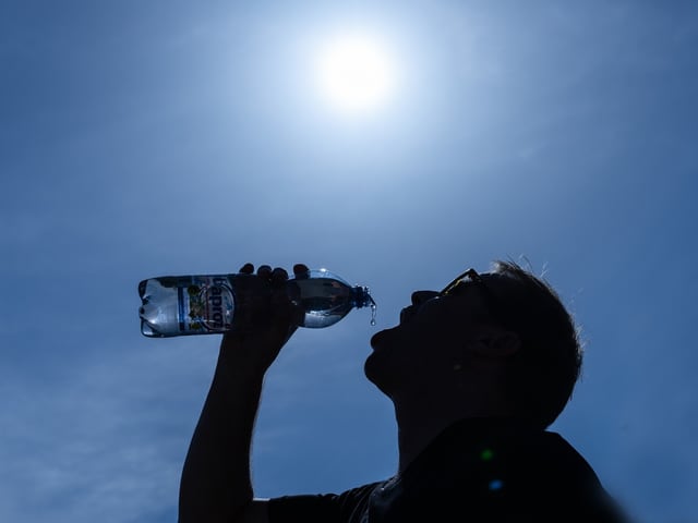 Silhouette einer Person trinkt Wasserflasche im Sonnenlicht.