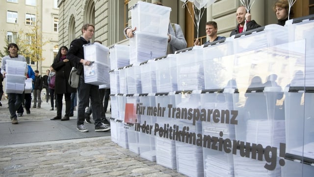 Personen laufen mit den Boxen, die Unterschriften enthalten, in Richtung Bundeshaus-West wahrend der Einreichung der Transparenz-Initiative.