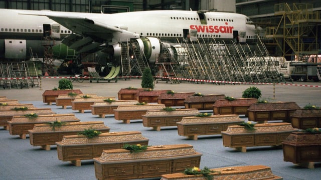 Särge und im Hintergrund ein Swissair-Flugzeug