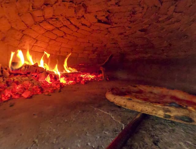 Pizza wird eine einem Pizzaofen gebacken.