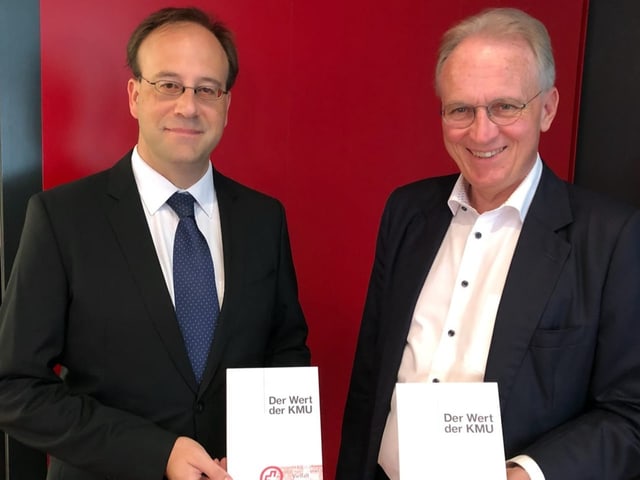 Henrique Schneider steht neben Hans-Ulrich Bigler. Beide halten ein Buch in der Hand mit dem Titel «Der Wert der KMU».