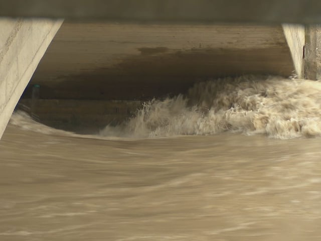 Stark strömendes Wasser unter einer Brücke.