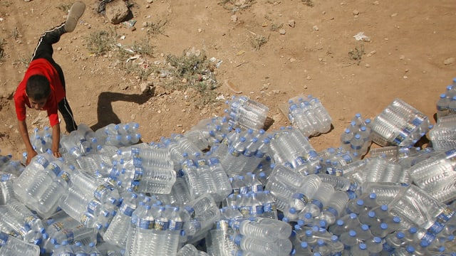 Hilfslieferung im Irak: Ein Kind bedient sich mit Wasserflaschen.