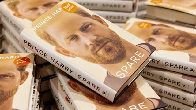 Ein Stapel Bücher, deren Cover das Gesicht von Prinz Harry ziert.