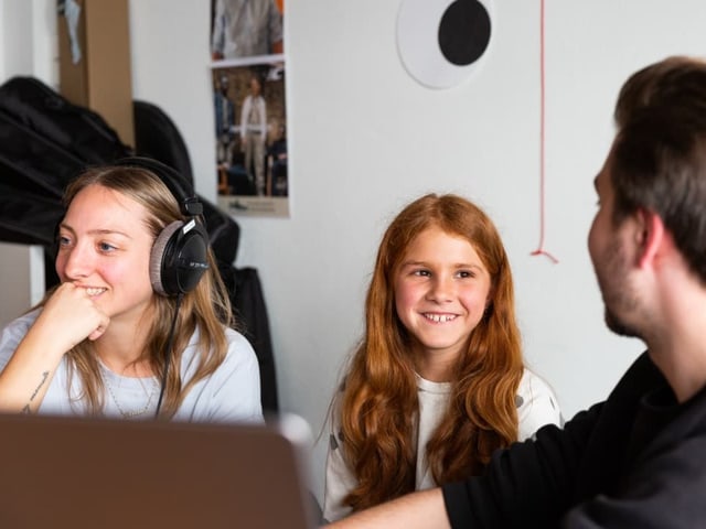 Adam erklärt Anna und Mia verschiedene Programme auf dem Computer.