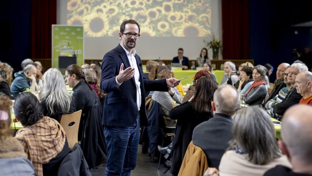 Balthasar Glättli steht gestikulierend zwischen den Grünen-Delegierten.