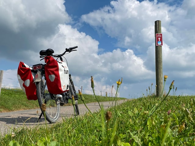 e-Bike steht auf dem Weg. Schild mit dem Veloweg Nummer neun.