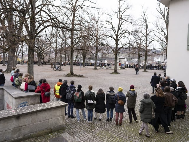 Blick auf einen Platz. Am Rand haben die Menschen eine Kette gebildet.