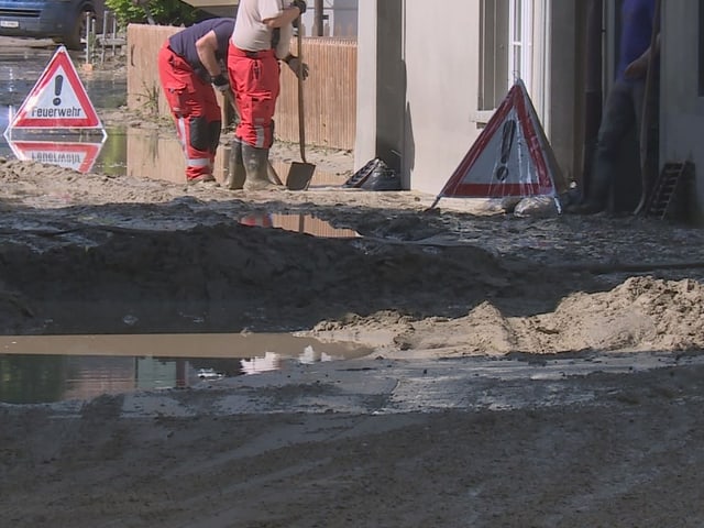 Arbeiter reparieren Strasse nach Überschwemmung.