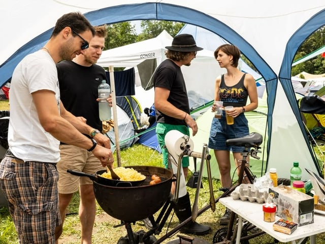 Junge Menschen grillieren unter einem Pavillon