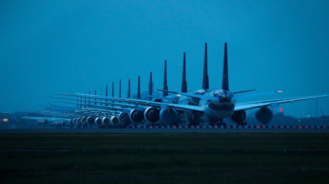 Flugzeuge in einer Reihe stehen in der Dämmerung.