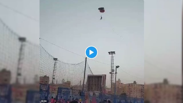 in der Luft Fallschirmspringer, unten Netze von Sportplatz udn Menschen, blauer Himmel