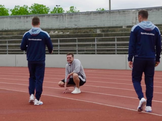 Mann kniet auf einem Sportplatz, sichtlich erschöpft.