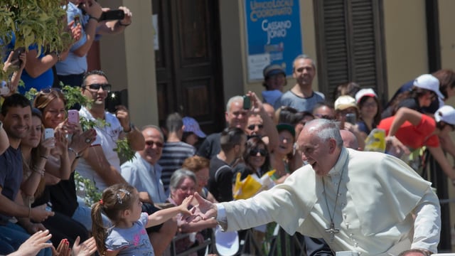 Der Papst und ein kleines Mädchen reichen sich die Hände.