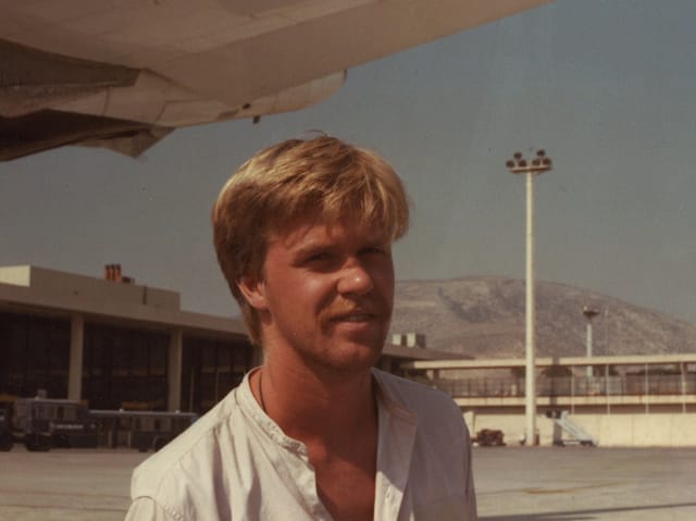 Junger Mann mit Schnauzer auf Flughafen.