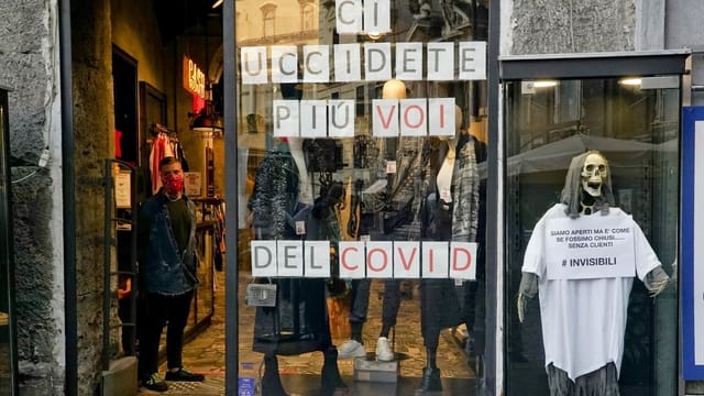 In einem Ladenschaufenster steht ein Skelett, daneben ein Schild mit der Aufschrift: Schämt euch, ihr tötet mehr von us als Covid.