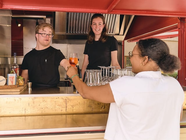 Menschen mit und ohne Beeinträchtigung arbeiten in einem Foodtruck.