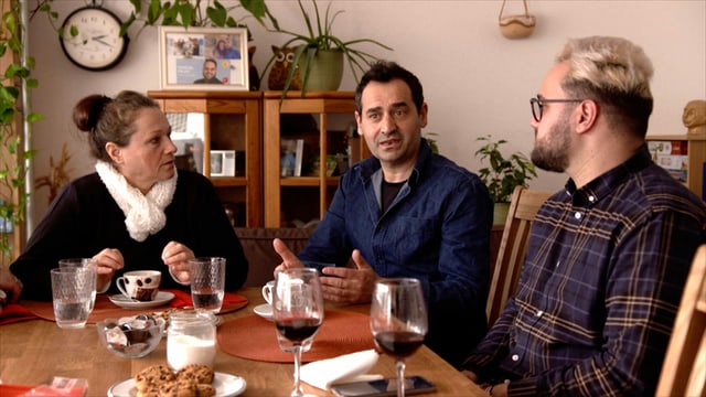 ein älterer Mann und eine Frau sitzen mit ihrem erwachsenen Sohn am Tisch