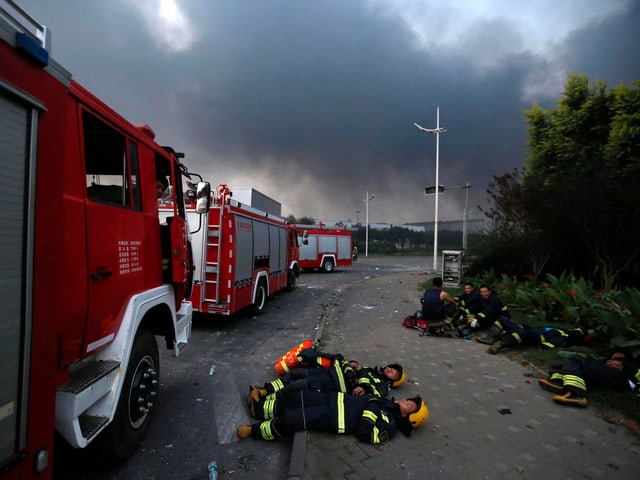 Feuerwehrleute liegen neben den Einsatzwagen auf der Strasse