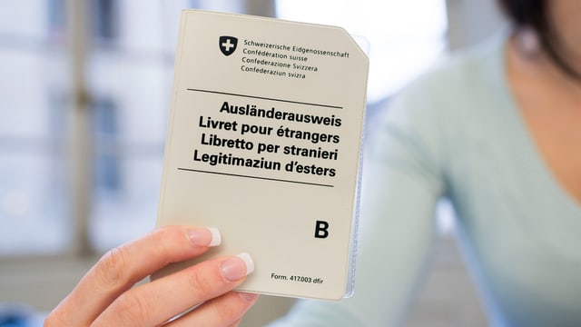 Angestellte einer Migrationsbehörde hält Ausländerausweis B in der Hand