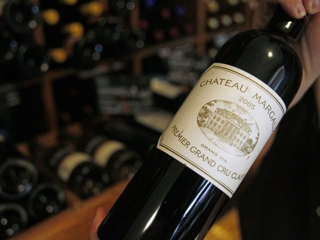 Person hält Flasche Château Margaux Wein im Weinkeller.