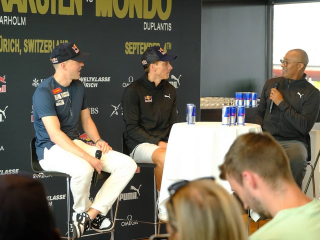 Zwei Sportler und Moderator bei einer Pressekonferenz