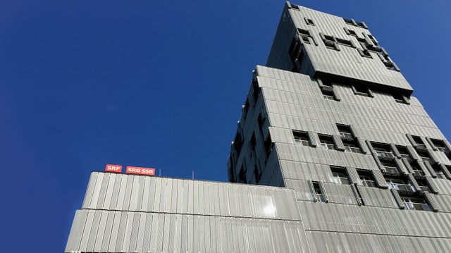 Ein graues Hochhaus mit beweglichen Fensterläden.