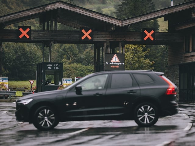 Schwarzes Auto vor geschlossenem Tor mit roten X-Zeichen.