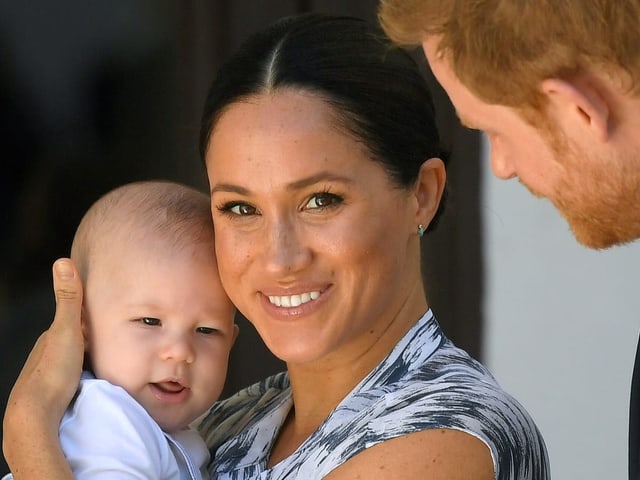 Herzogin Meghan hält Archie im Arm und lächelt.