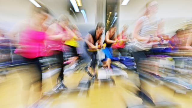 Eine Gruppe beim Stepaerobic, verschwommen aufgenommen.