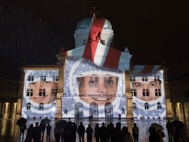 Projektion:  Die fröhlichen Gesichter von Armstrong, Aldrin und Collins.