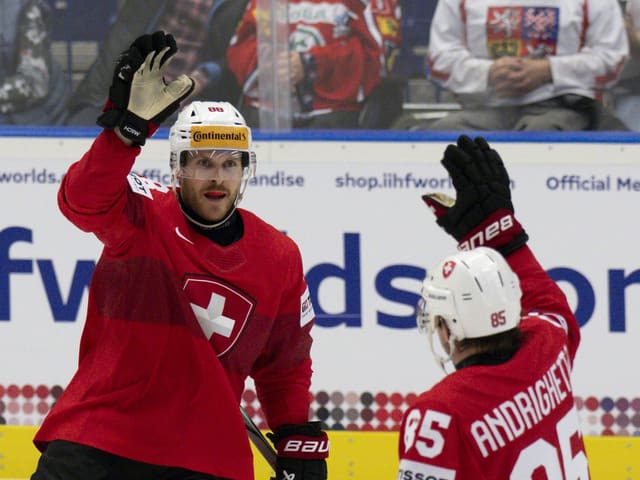 Zwei Eishockeyspieler in roten Trikots beim High-Five.