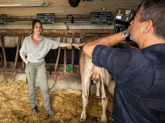 Frau im Stall mit Kuh, wird fotografiert.