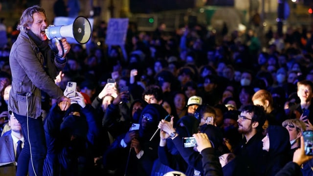 Demonstrierende hören einem Protestanten mit Megafon zu