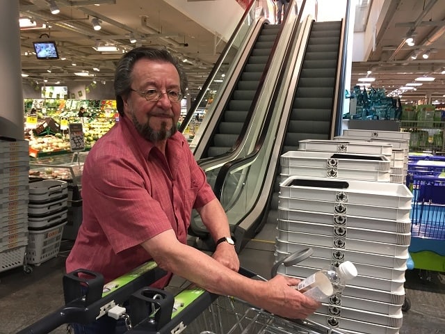 Der Erfinder hält in einem Coop-Laden eine PET-Flasche unter seine Einkaufswagenlupe.