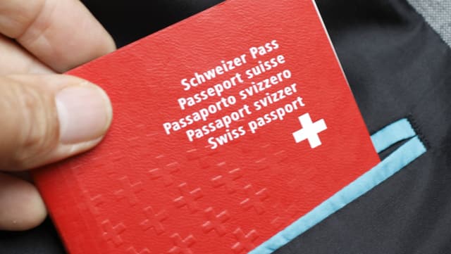 Eine Hand zieht einen Schweizer Pass aus einer Vestontasche.