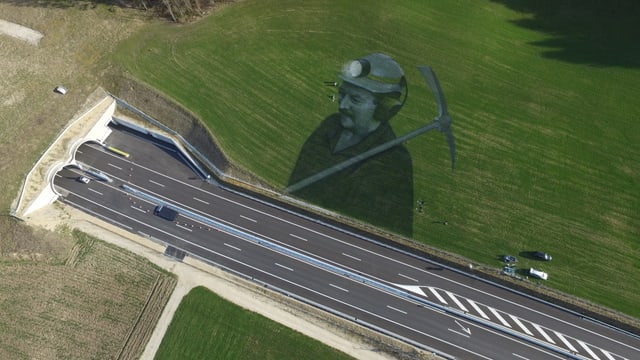 Porträt eines Tunnelarbeiters in der Wiese neben der Autobahn.