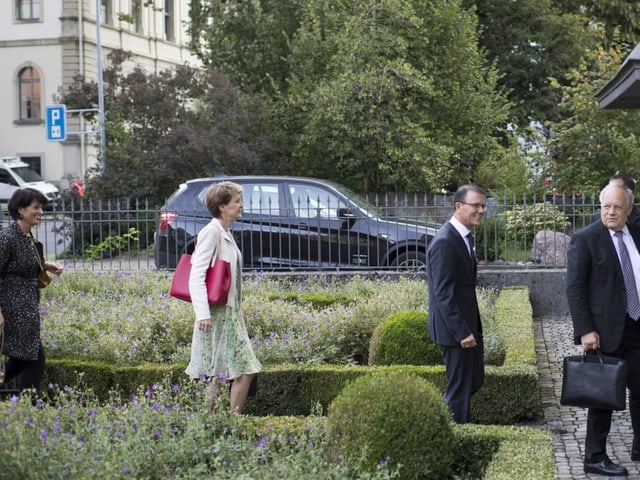 Bundesräte in einem Garten in einen Eingang gehend.