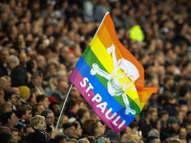 Ein Junge schwenkt in einem Stadion eine Fanflagge des FC St. Pauli